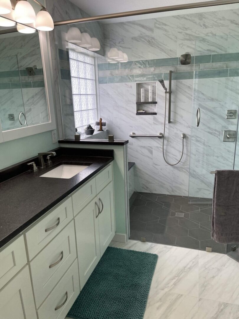 A bathroom with a sink, shower and mirror.