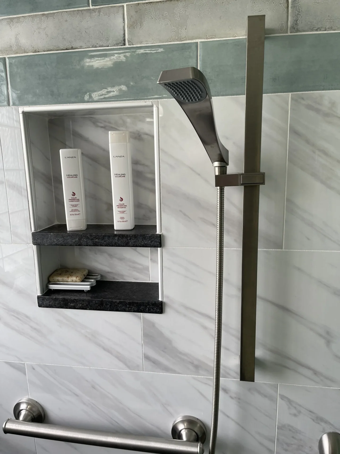 A shower with two shelves and a hand held shower head.