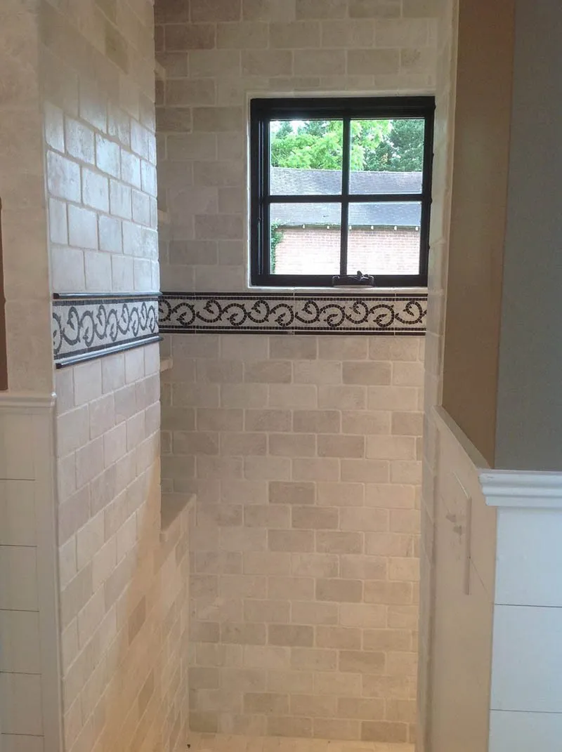 A bathroom with a window and tiled walls