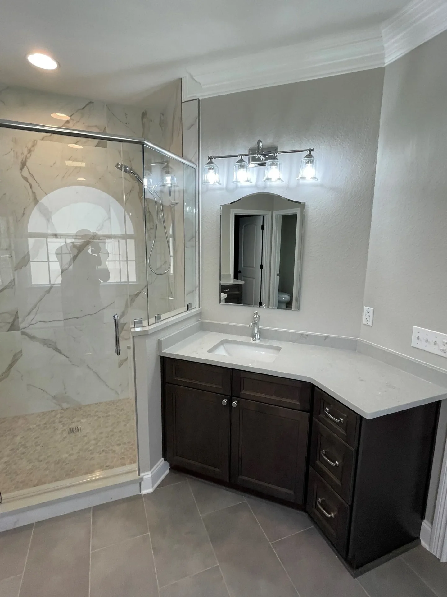 A bathroom with marble walls and floors, and a large mirror.