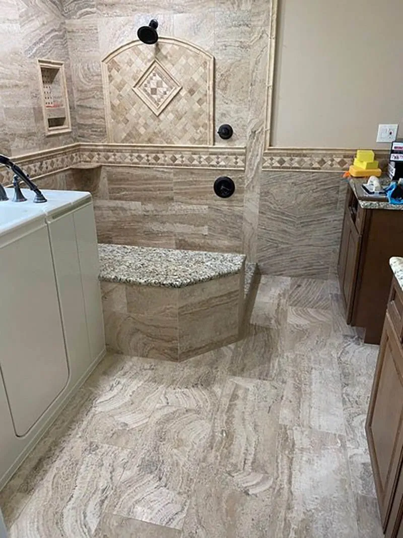 A bathroom with marble tile and granite counter tops.