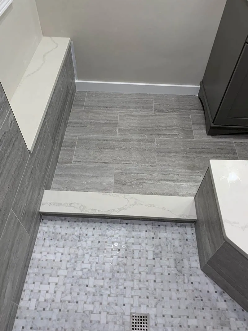 A bathroom with gray tile and white marble.