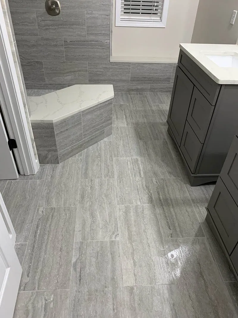 A bathroom with gray tile and white counters.